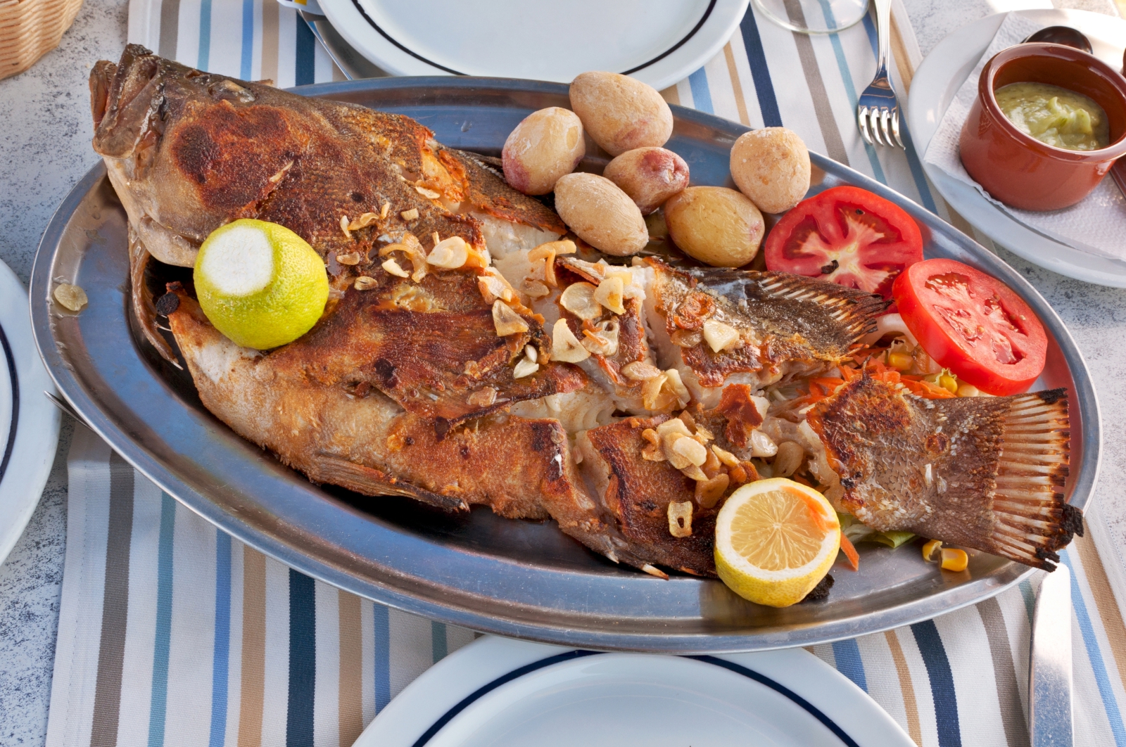 'Typical Canarian Roasted sea fish on plate with tomatoes, potatoes, lemon and spices' - Lanzarote